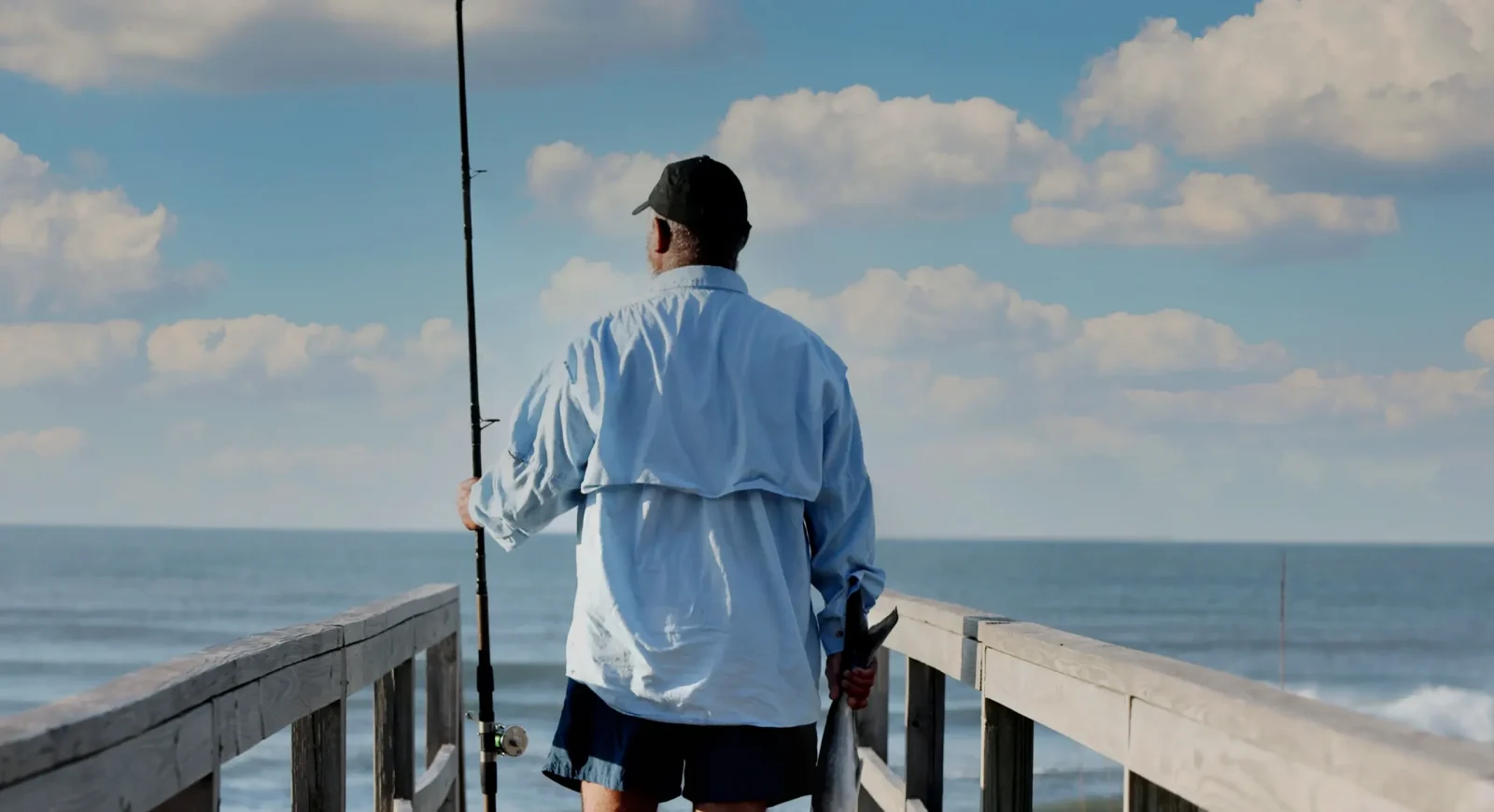 A man with fishing gear looks out on the ocean on a beach in North Carolina