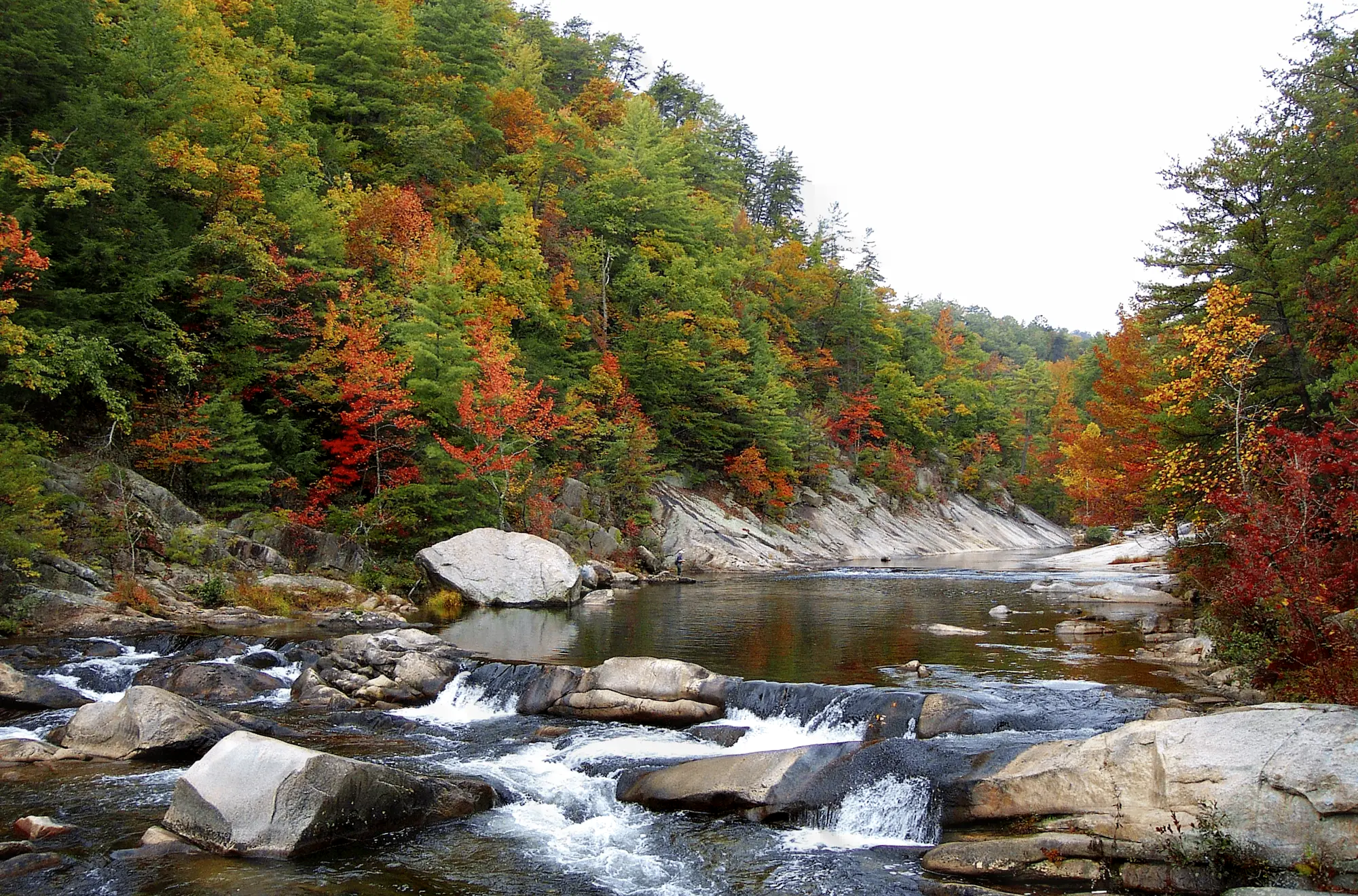 Water flows through a large creek with rocks and fall colors in Lenoir, North Carolina